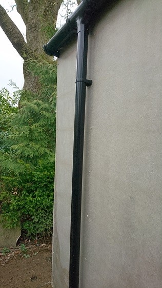 Garden room's black PVC guttering and a downpipe connected to a local soakaway